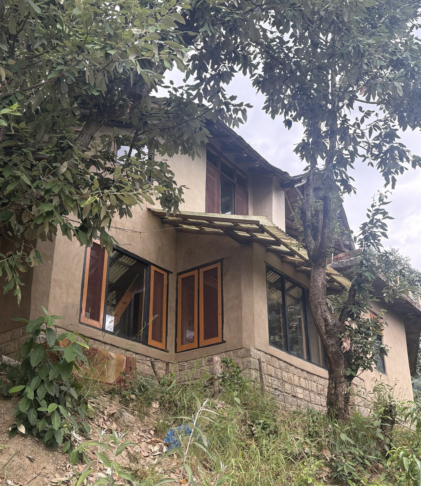 Earthen building set among trees, its walls raised on a stone plinth