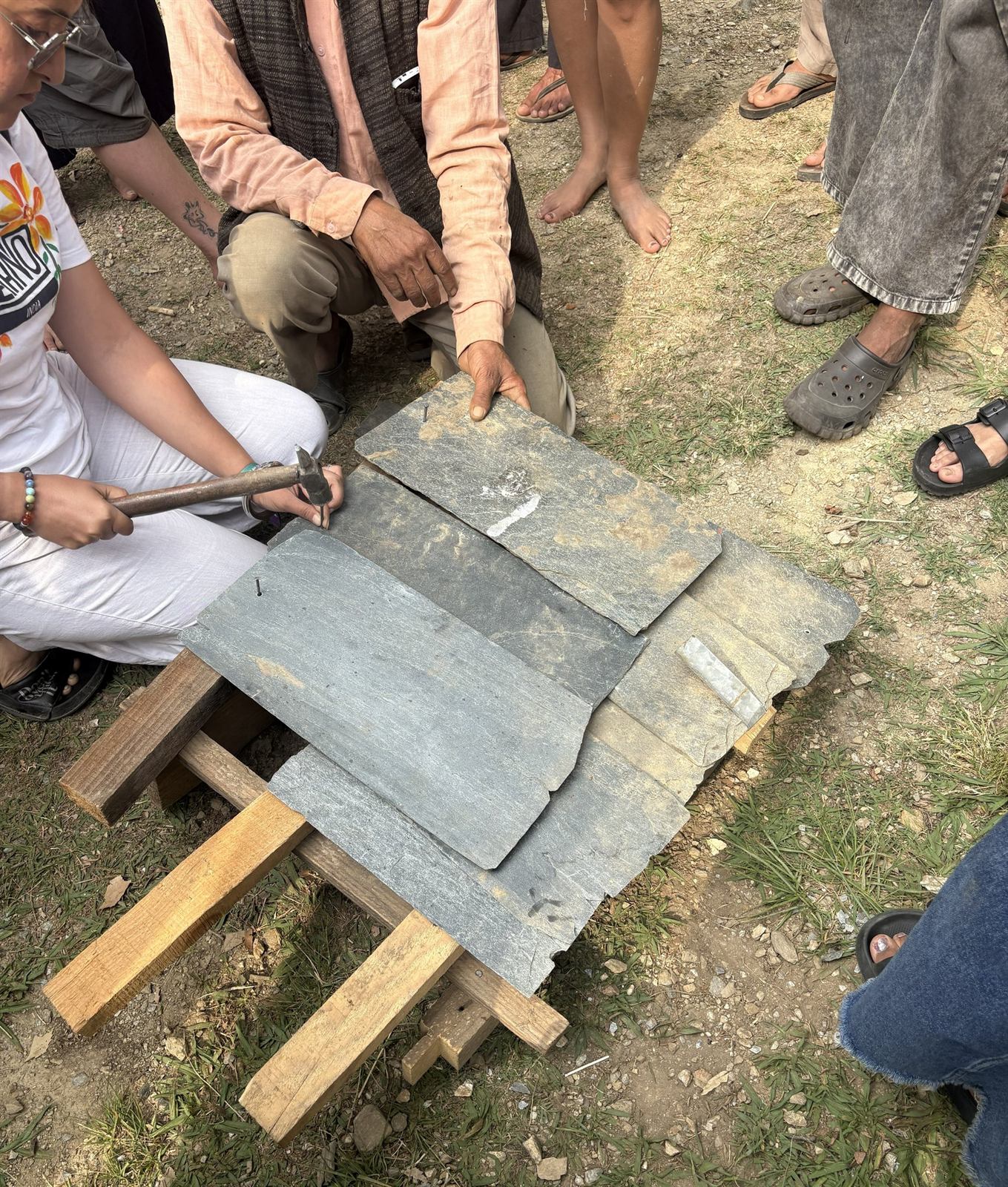 Participants learning to trim and lay Kangra slate tiles on a timber batten frame